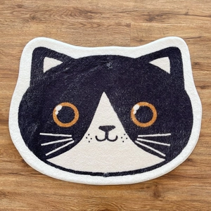 Tapis de sol mignon en forme de chat noir et blanc sur un sol en bois marron clair