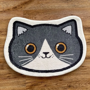 Détail du paillasson en forme de chat avec texture en peluche douce et yeux orange vifs