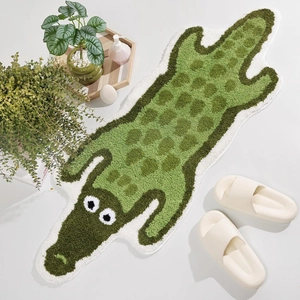 Close-up of a green cartoon crocodile bath mat with soft tufted texture in a home setting