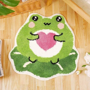 Detail of soft green cartoon frog plush rug featuring heart embroidery and lotus leaf base