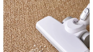 Close-up of vacuum head cleaning white debris on brown sisal texture carpet
