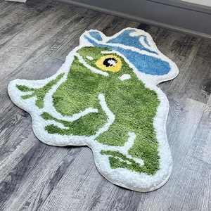 Close-up of a soft green frog rug wearing a blue cowboy hat on dark wood floor