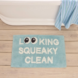Detail of plush light blue bath mat featuring playful white letter text on wood floor