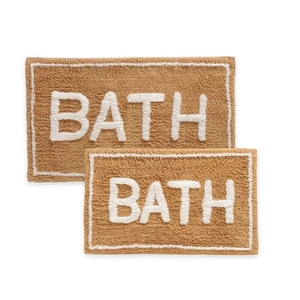Detail of plush brown bath mat with white BATH lettering and reinforced stitched edges