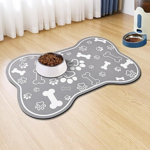 Bone-shaped pet feeding mat with paw prints on light wooden floor in a cozy home setting