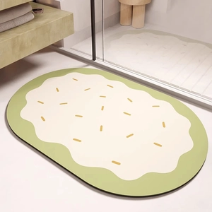 Détail d'un tapis de bain ovale absorbant style dessin animé aux tons vert et crème doux