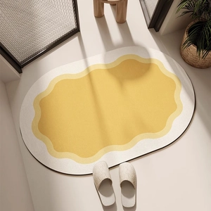 Gros plan sur un tapis de bain ovale avec motif de vagues jaunes et bords antidérapants