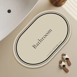 Detail view of oval beige diatomite bathroom mat with elegant black double border and text