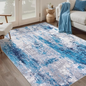 Close-up of modern abstract rug with blue and grey splash ink texture on wooden floor
