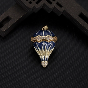 Detail of hot air balloon pendant with blue enamel and white crystals on black surface