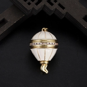 Detailed view of egg-shaped hot air balloon pendant with gold metal and white enamel