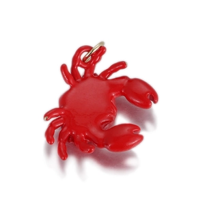 Détail macro d'un pendentif crabe en émail rouge avec anneau en métal doré poli