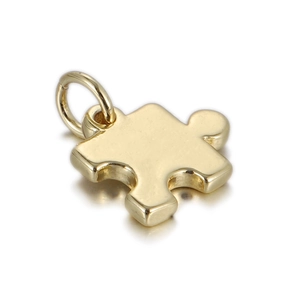 Vue macro d'un pendentif en forme de pièce de puzzle doré avec finition polie brillante
