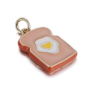 Close-up of cute enamel bread slice pendant with a heart egg on white mirror background