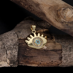 Close-up of golden Evil Eye pendant with cubic zirconia on rustic dark wood background