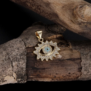 Detailed close-up of golden evil eye sunburst pendant with blue stone and zircons