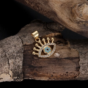 Detailed view of the 14k gold Evil Eye charm with zircon stones on rustic wood