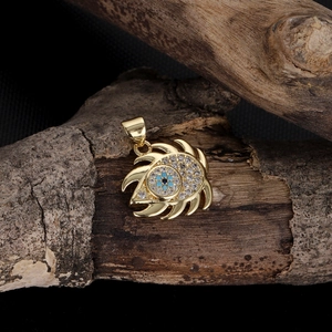Detailed view of evil eye charm with blue zircon on textured wood stand