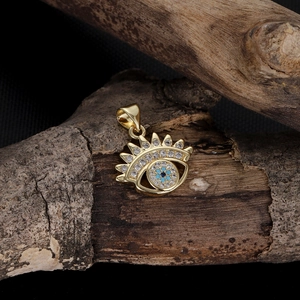 Detailed shot of golden evil eye pendant with blue zircon on natural wood branch
