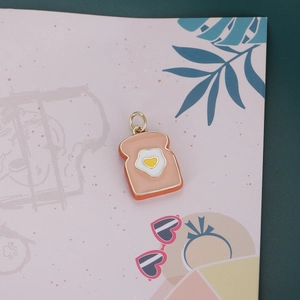 Cute enamel toast pendant with heart-shaped fried egg design on a pink artistic background
