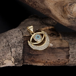 Detailed view of gold evil eye moon pendant with white zircons on dark wood texture