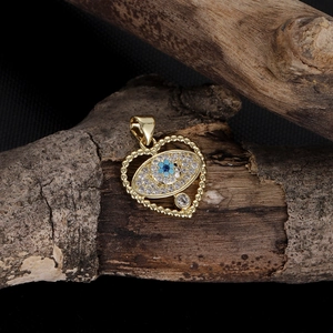 Macro detail of gold heart pendant with evil eye motif and sparkling zircon stones