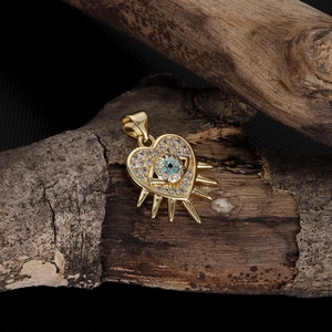 Macro detail of heart evil eye pendant with cubic zirconia and golden sunburst rays