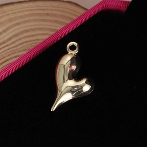 Pendentif cœur artistique en métal doré avec finition polie sur fond de velours noir
