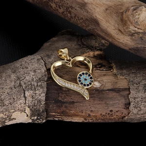 Detailed view of gold heart pendant with evil eye stones and zircons on wood
