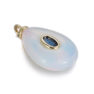Macro view of teardrop natural stone pendant with blue zircon center in gold setting