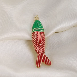Macro detail of tropical fish pendant with red and green enamel and gold-plated scales