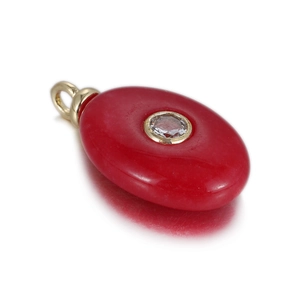 Macro detail of red stone pendant with center zircon inlay and golden metallic bail