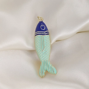 Macro detail of enamel tropical fish charm with golden scales on satin background