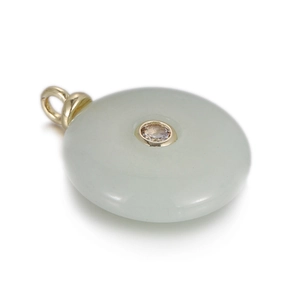 Detailed view of a green jade donut pendant with gold inlay and a sparkling zircon stone