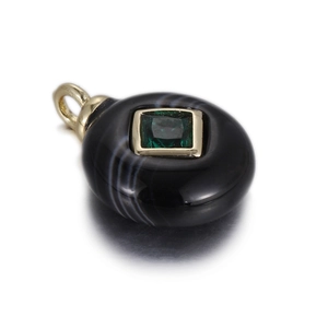 Macro detail of black agate pendant with green square zircon inlay and gold hardware