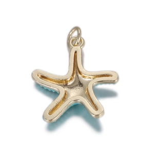 Gros plan d'un pendentif étoile de mer doré avec émail bleu clair et anneau en métal