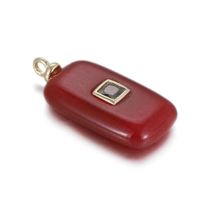 Macro view of rectangular red stone pendant with golden square inlay and small gemstone