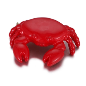 Gros plan d'une breloque crabe rouge vif avec finition émail brillant sur fond miroir