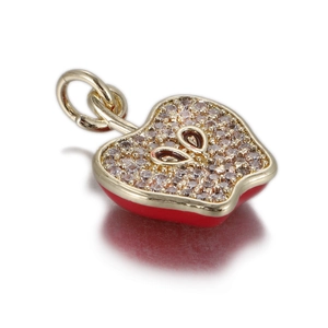 Macro view of gold-plated apple pendant with red enamel and sparkling crystal inlay