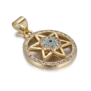 Macro shot of gold Hamsa hand pendant with blue evil eye and sparkling zircon stones
