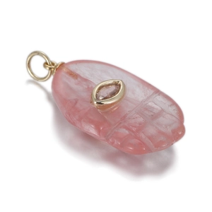 Macro view of hand-carved pink quartz fish pendant with inlaid gem and golden metal loop