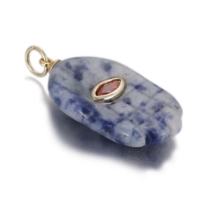 Detail of Hamsa-shaped sodalite stone pendant with red gem and gold-plated bail