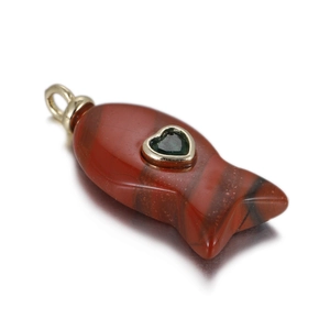 Macro shot of fish-shaped natural red stone pendant with green heart gemstone and gold loop