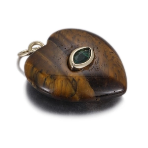 Detail of heart-shaped tiger eye stone pendant with centered green gem and golden ring