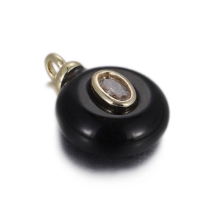 Macro shot of a black round jade pendant with a gold-set oval light brown gemstone inlay