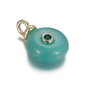 Detailed macro view of a green stone pendant with a gold rim and inlaid emerald gem