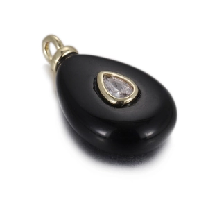 Macro detail of black teardrop stone pendant with gold clasp and pear-cut zircon inlay