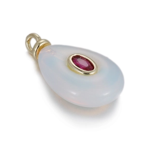 Detail shot of a teardrop opal pendant with an oval red gemstone in a gold setting