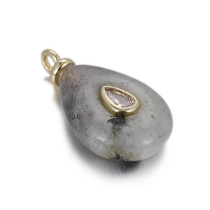 Macro view of teardrop natural grey stone pendant with inlaid white zircon and gold plating
