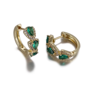 Détail de boucles d'oreilles dorées avec pierres vertes en goutte et micro-cristaux